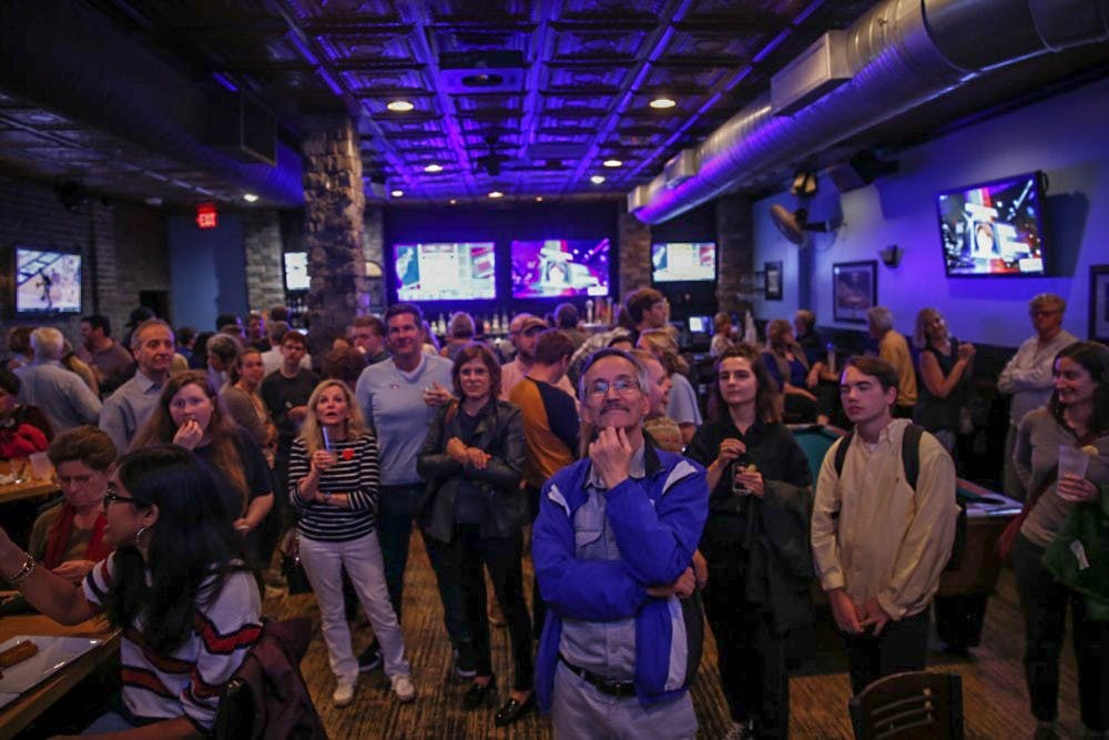 <p>Crowds look on to voting updates at Might as Well, where the Orange County Democratic Party held an election party Tuesday.&nbsp;</p>