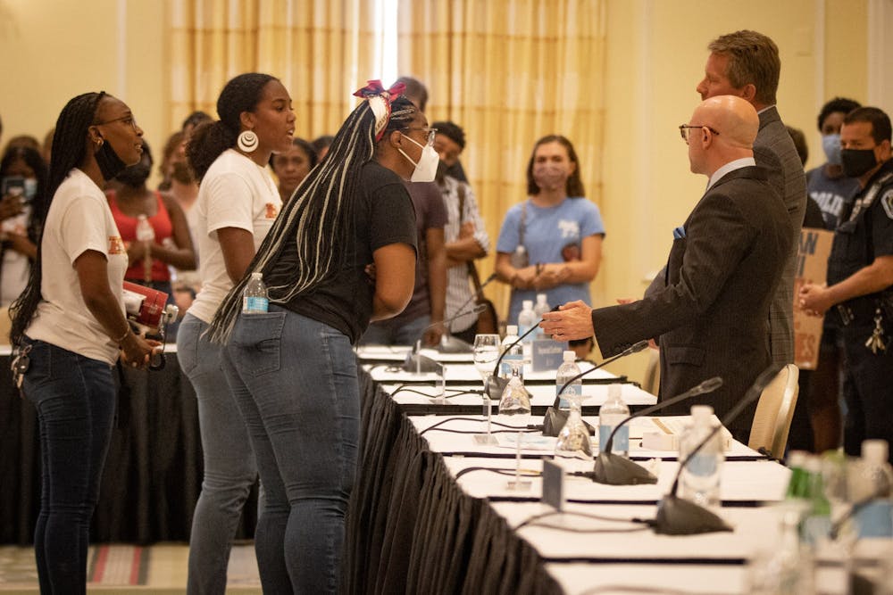 Student activists from the Black Student Movement speaks to Board of Trustees President Gene Davis and UNC Chancellor Kevin Guskiewicz after the BOT meeting that granted tenure to Nikole Hanna-Jones.