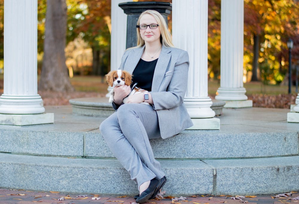 Senior environmental studies major and public policy minor Caroline Pharr spearheaded the petition to build a permanent ramp at the Old Well. She sits on the steps of the Old Well on Nov. 15  with her dog Franklin who is training to become a service animal.