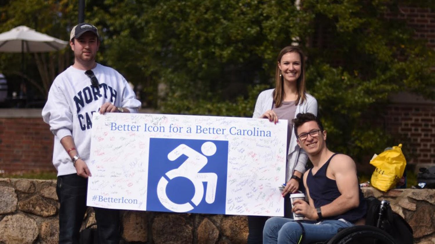 Students Mark Ellard, a senior history major (left), Marie Payne, a senior exercise and sports science major, and Chris Corsi, a junior psychology major in the pit on Thursday, trying to gain signatures in other to change accessibility signs on campus to a more active looking sign.