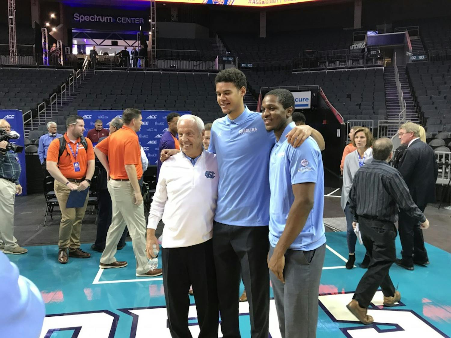UNC men's basketball head coach Roy Williams and guards Cam Johnson and Kenny Williams pose for a picture at the Spectrum Center for ACC men's basketball media day on Oct. 24.