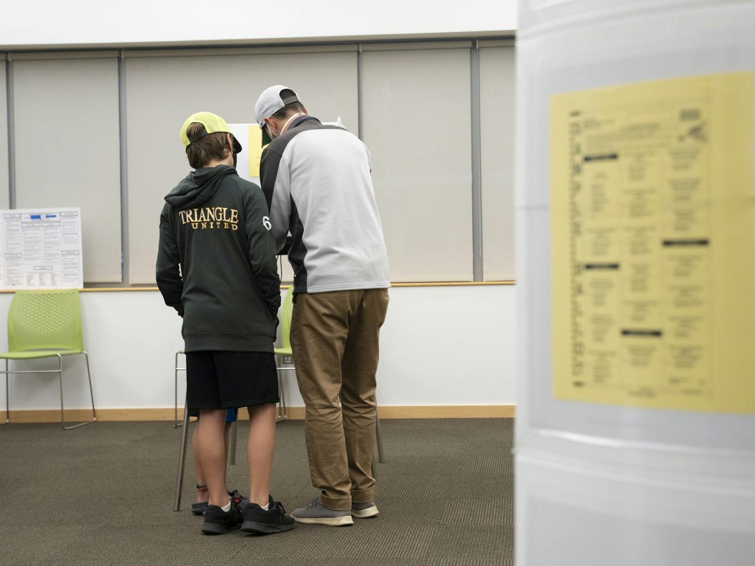 A father brings his sons to watch him vote at the Chapel Hill Public Library voting site in Chapel Hill, N.C. on Tuesday, Nov. 8, 2022, when the polls opened on midterm election day.