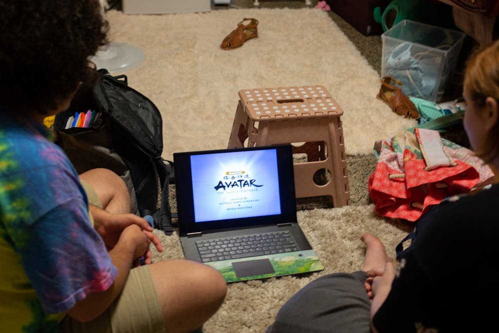 DTH Photo Illustration. Two people watch Avatar: the Last Airbender on a laptop.