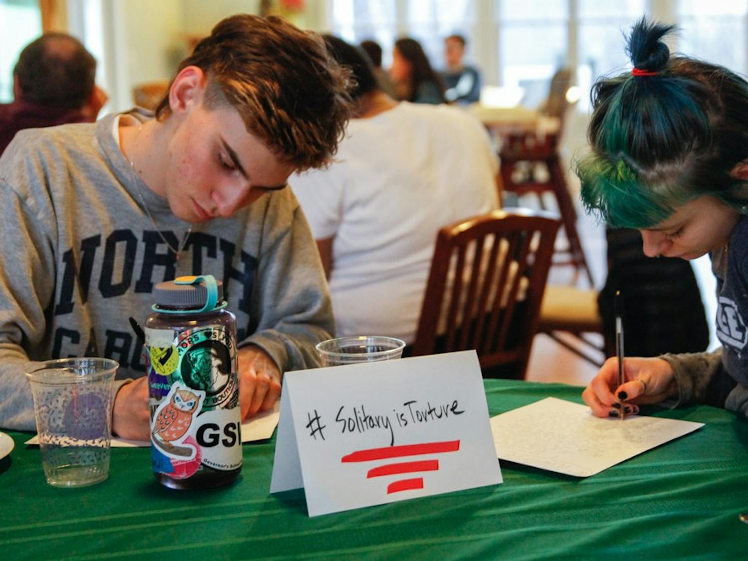 (From left to right) Sergio Jimanez, senior at Chapel Hill High School and Jasper Cobb, senior at Middle College High School at Durham Technical Community College, write letters to  Kanautica Zayre-Brown at the Queer Family Gathering dinner at a community building in Carrboro, Tuesday, March 19, 2019. Kanautica is a trans woman incarcerated at a men's prison and who has been in solitary confinement for 17 days. The letters are meant to help Kanautica maintain her mental health during her confinement until she can be moved into a women's facility.