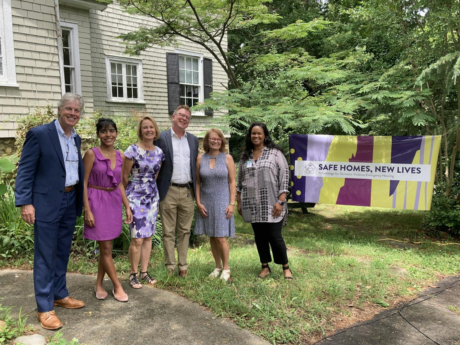 
The speakers at the Safe Homes Celebration on June 4, 2021 gather for a photo. From left to right: Gary Bowen, PhD, Dean of UNC School of Social Work; Natalia Rivadenerya, Emergency Housing Coordinator, Compass Center for Women and Families; Gillian Hare, Board Chair, Compass Center for Women and Families; Martin Baucom, Vice-President for Development, UNC Health Foundation; Jeannie Denuo, Safe Homes Campaign Co-Chair and Compass Center Board Member; Loryn Clark, Deputy Town Manager for the Town of Chapel Hill. Photo courtesy of Ann Simpson/Compass Center. 
