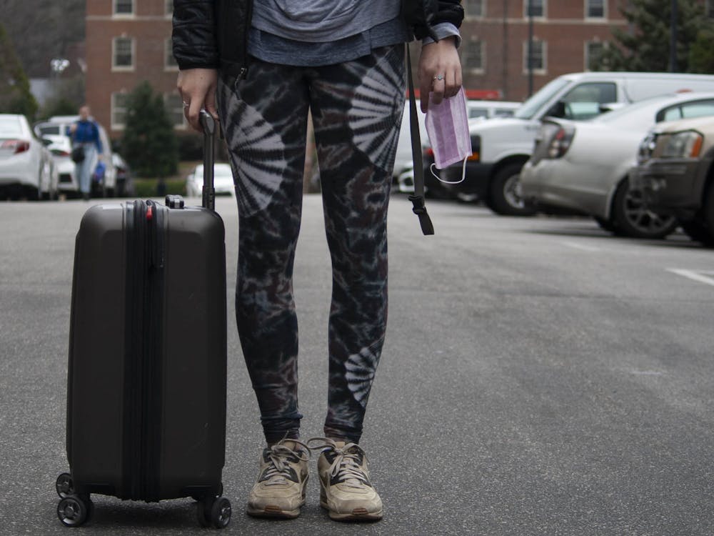 DTH Photo Illustration. A UNC student holds a suitcase and a surgical mask on campus on Tuesday, March 3, 2020. The coronavirus has cancelled various study abroad programs.&nbsp;