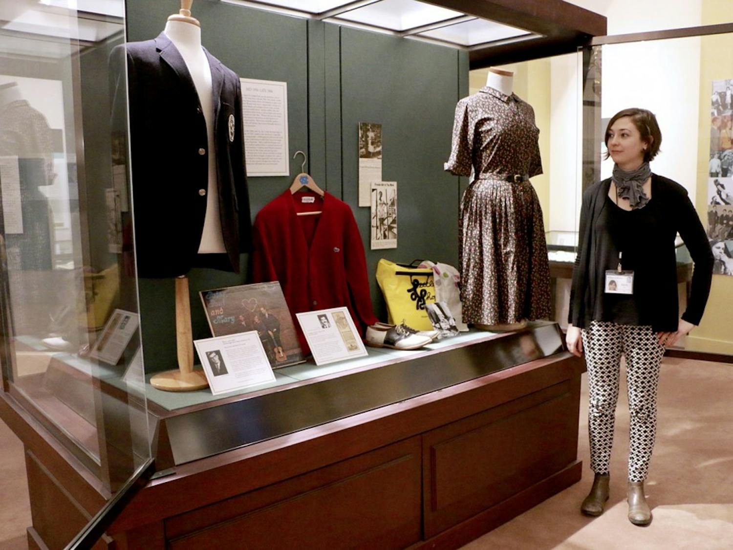 Emily Jack, the Digital Projects and Outreach Librarian for the North Carolina Collection Gallery, stands next to a display featuring clothing from the 1950s-1970s in the exhibition From Frock Coats to Flip-flops: 100 Years of Fashion at Carolina. The exhibition opened in Wilson Library this Thursday and includes nearly 60 items of clothing along with photographs, news ads, articles and excerpts from old student handbooks. 