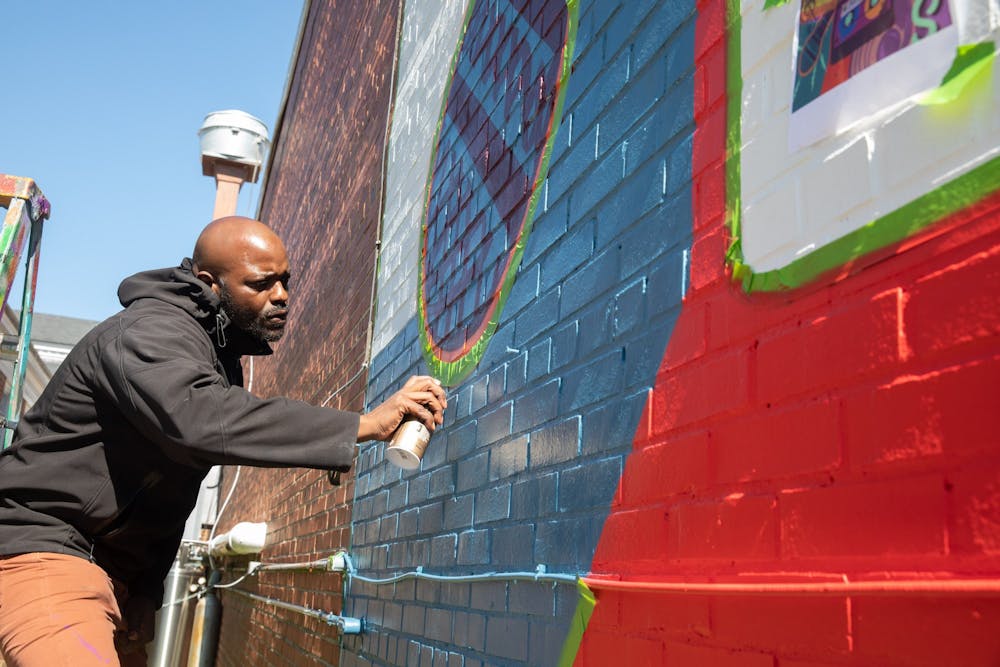 Local artist Artie Barksdale works on a mural located on 108 Henderson St. for the upcoming Hip Hop South Festival on Tuesday, April 19, 2022. The festival takes place on April 22 and April 23 in venues around Chapel Hill and Carrboro.
