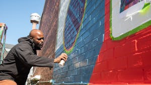 Local artist Artie Barksdale works on a mural located on 108 Henderson St. for the upcoming Hip Hop South Festival on Tuesday, April 19, 2022. The festival takes place on April 22 and April 23 in venues around Chapel Hill and Carrboro.