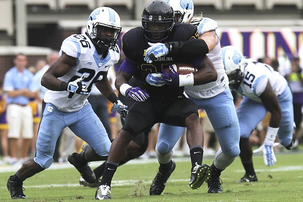 ECU's Breon Allen (25) is brought down by Jeff Shoettmer (10) and Dominiquie Green (26).