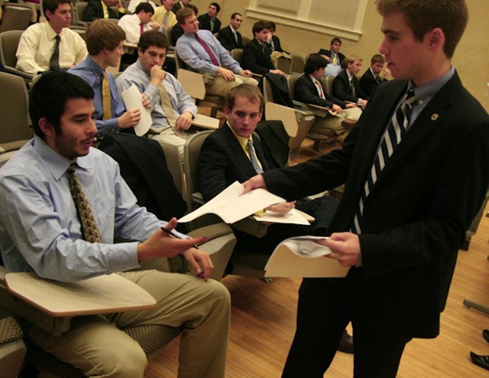 Todd Stacy, junior and president of Pi Kappa Phi  fraternity, hands out testing materials Thursday night.