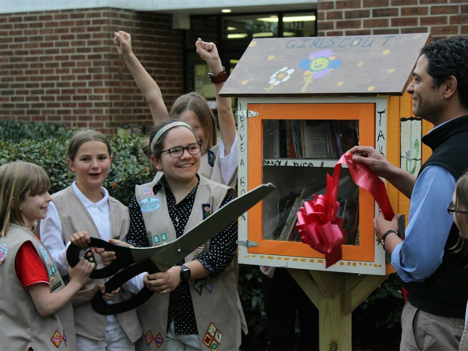 Girl Scout Troop 3064 and Mayor Mark Kleinschmidt officially install the Little Free Libraries with a ribbon-cutting ceremony at Community Center Park on Thursday evening. 