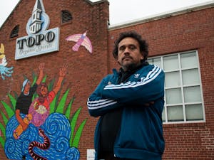 Renzo Ortega poses for a portrait with his work "Successions". The new mural at TOPO Distillery pays tribute to family bond dynamics, especially those of family members that have left and have yet to return.