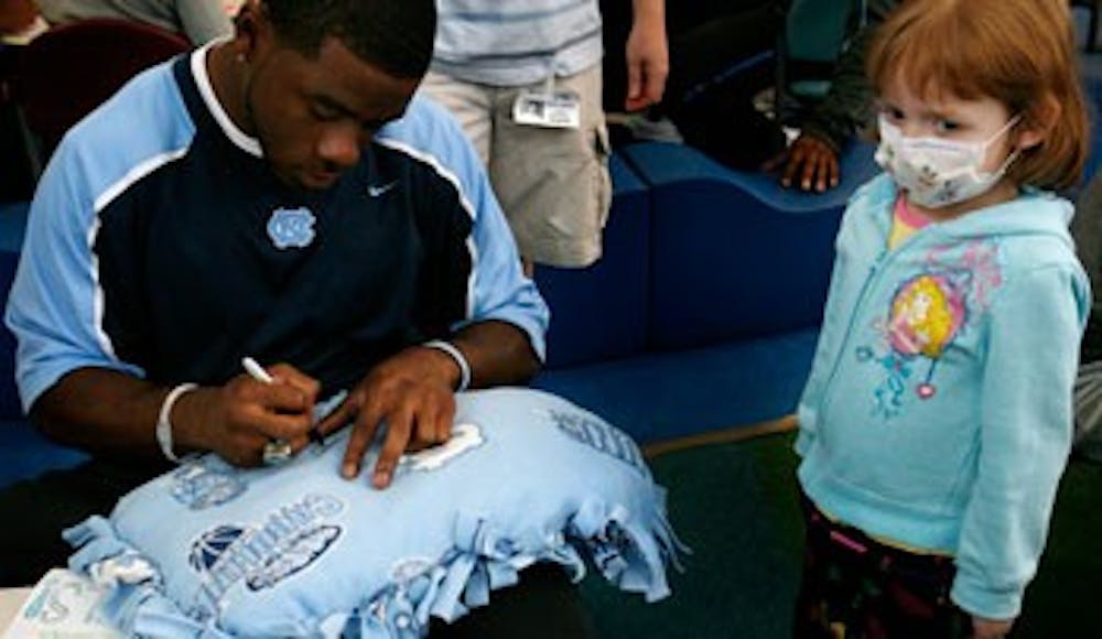 Shaun Draughn signs the homemade pillow of Leslie Hughbaker, a patient at N.C. Children’s Hospital. DTH/Andrew Dye