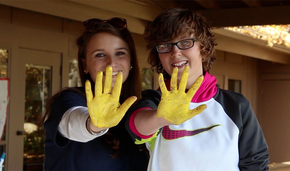	Molly Laux and Valerie King show their painted hands after contributing their handprints to a banner that says, “Together we are brave.” 