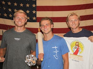 Chapel Hill Housemates Harrison Schertzinger, Diego Vallota, and Henry Schertzinger, pose in front of an American Flag and show off NANDO's merchandise. Photo Courtesy of NANDO's Donuts. 