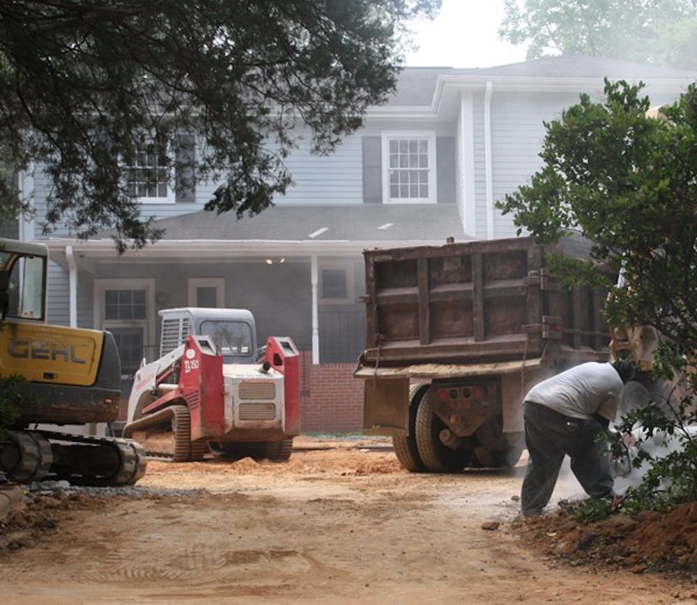 Construction crews work behind the Kappa delta sorority house, which is sinking. Crews are working to install a drainage system that will remove excess water from the property and to repair the foundation of the house.