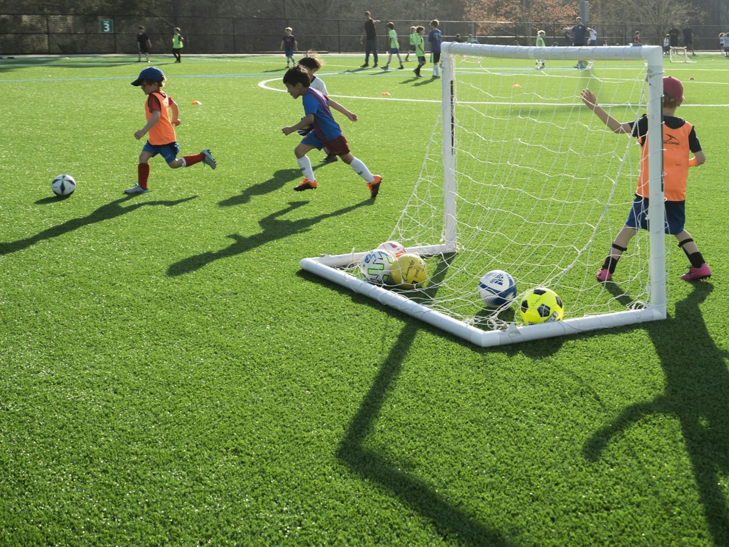 Young soccer players do a drill with their team on the new turf at Cedar Falls Park in Chapel Hill, N.C., on Thursday, Mar. 23, 2023. The Town of Chapel Hill held a ribbon-cutting ceremony to celebrate the freshly redone, environmentally-friendly turf for the multi-purpose field.