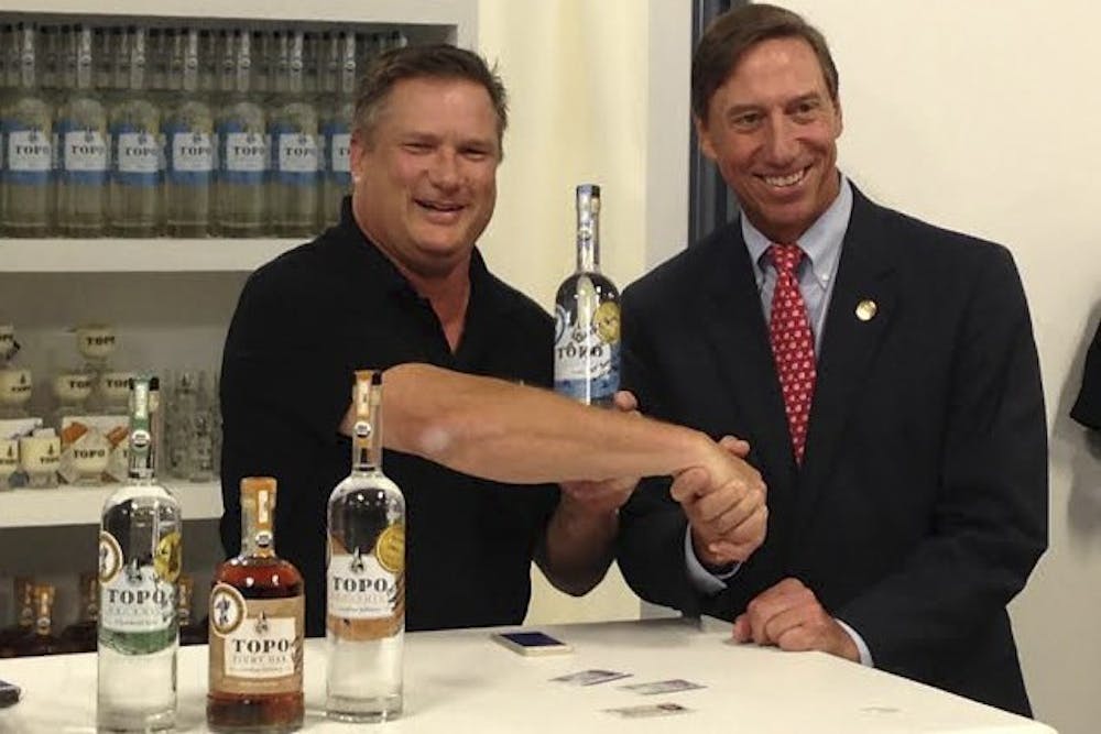 TOPO Distillery owner Scott Maitland (left) sells liquor to state Sen. Rick Gunn.