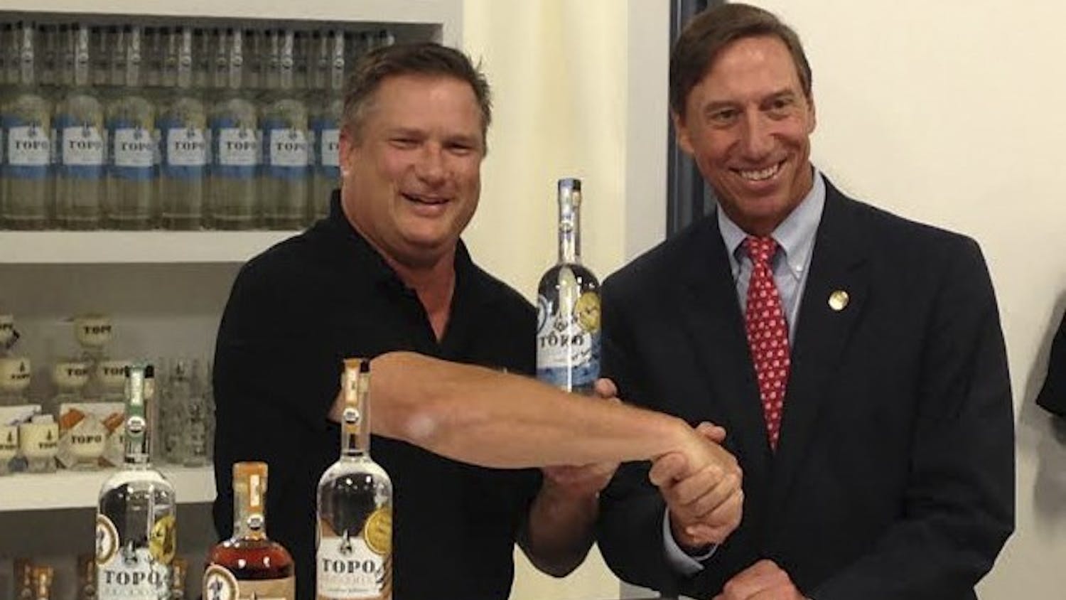 TOPO Distillery owner Scott Maitland (left) sells liquor to state Sen. Rick Gunn.