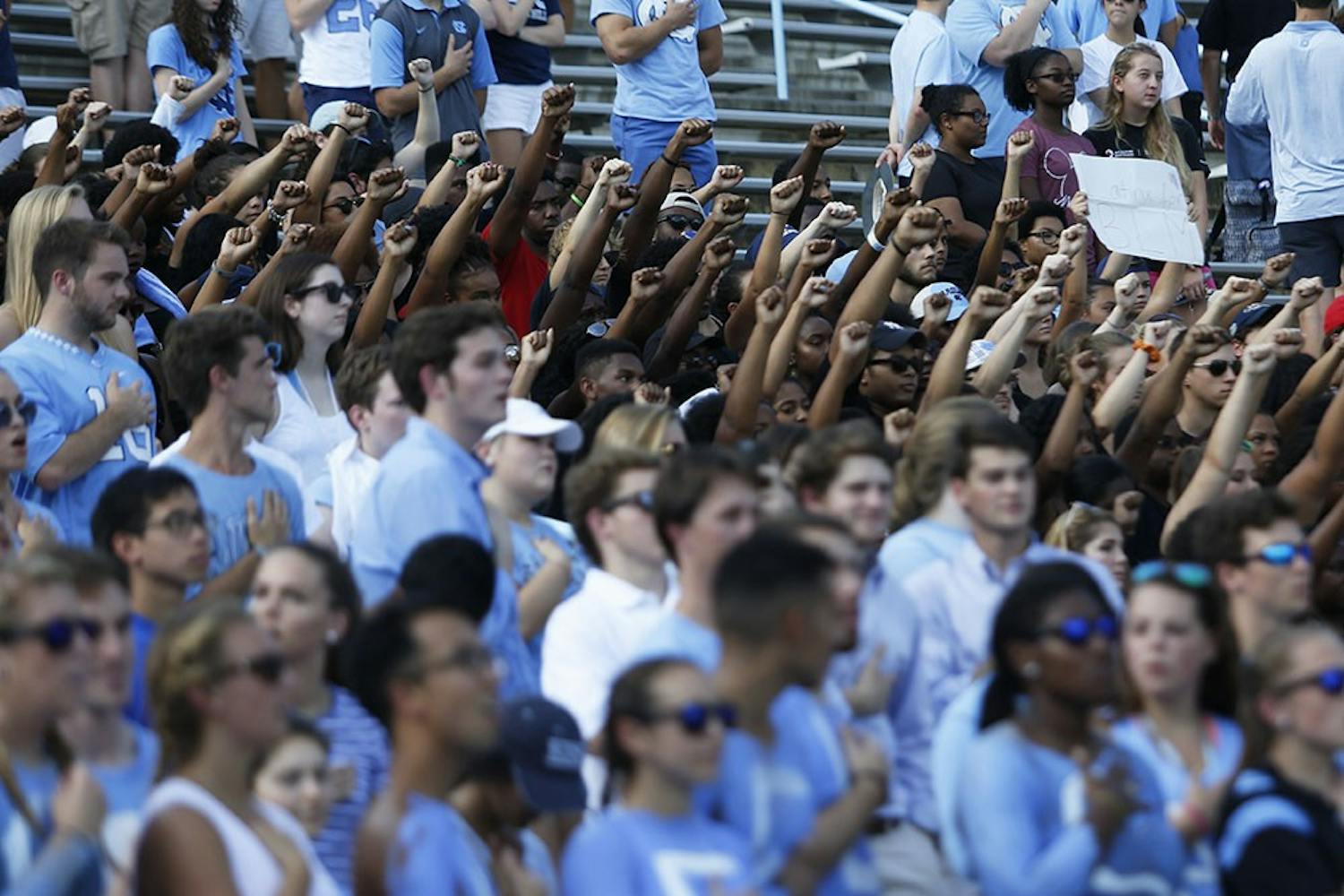A group of UNC students dressed in all black and sat with their fists raised during the national anthem before the UNC football game on Saturday.