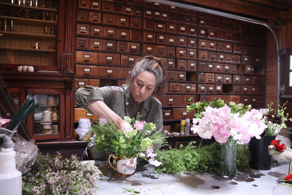 <p>Morgan Howell Moylan, owner of West Queen Floral Studios in Hillsborough, NC, works on a centerpiece on Friday, April 8, 2022, for an upcoming wedding.</p>