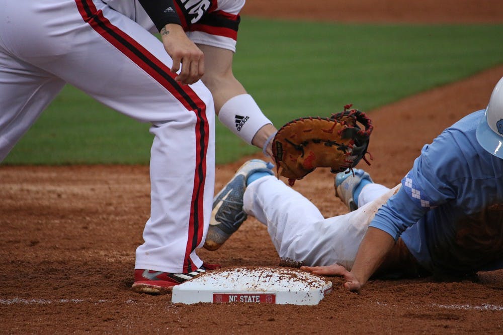 An NCSU player attempts to tag out Eli Sutherland (3) at first base during the baseball game against NCSU on Thursday.