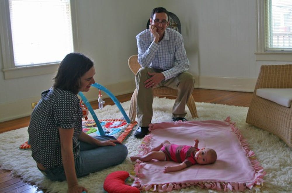 Josh Levy sits with his wife, Tina Levy, and five-month-old daughter, Louisa Rose, in their dining-room-turned-playroom in the couple’s Durham home. Josh Levy works in the mornings and comes home to take care of Louisa Rose in the afternoons while Tina is as work.