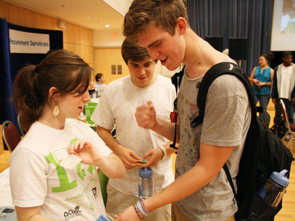 Freshmen Huston Julian, right, and Michael Touloupas, middle, get temporary tattoos from Natalia Posthill at Campus Sustainability Day.
