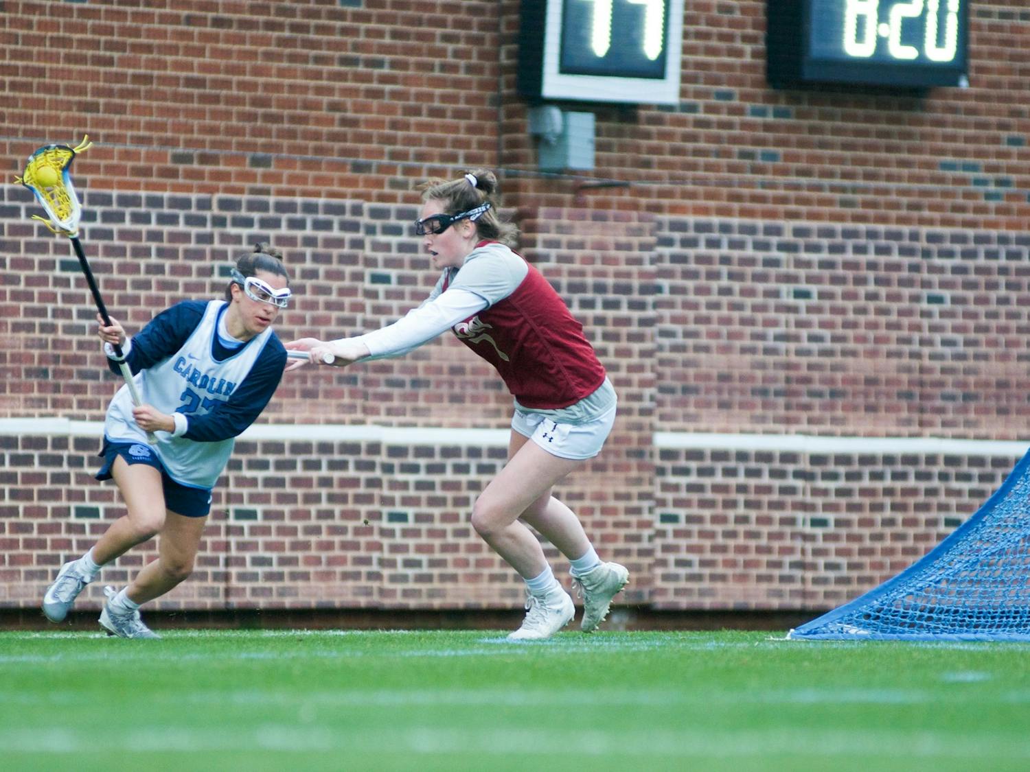 UNC senior midfielder Marisa Divietro (27) charges past Elon freshman defender Hannah Mccarthy (7) to attempt a shot on goal. The Tar Heels would start off the season with a 20-3 victory over Elon during the exhibition match on Feb. 1, 2020, at Dorrance Field. 