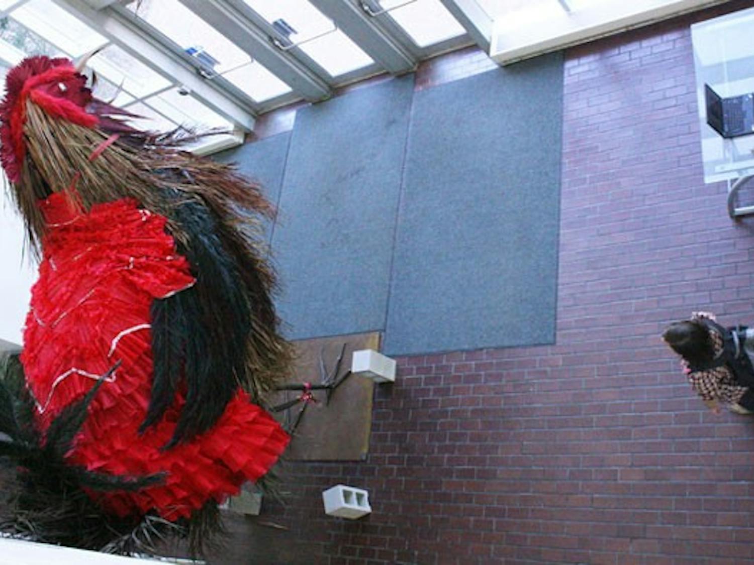 A student observes the giant rooster constructed in the lobby of the Hanes Art Center. DTH/Erin Hull