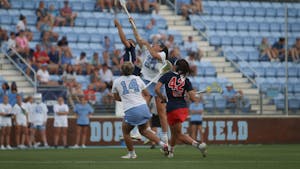 Junior midfielders Livi Lawton (14) and Olivia Dirks (27) run and jump for the ball during a faceoff in the NCAA quarterfinals. At halftime, UNC is losing 3-4 to Stony Brook.