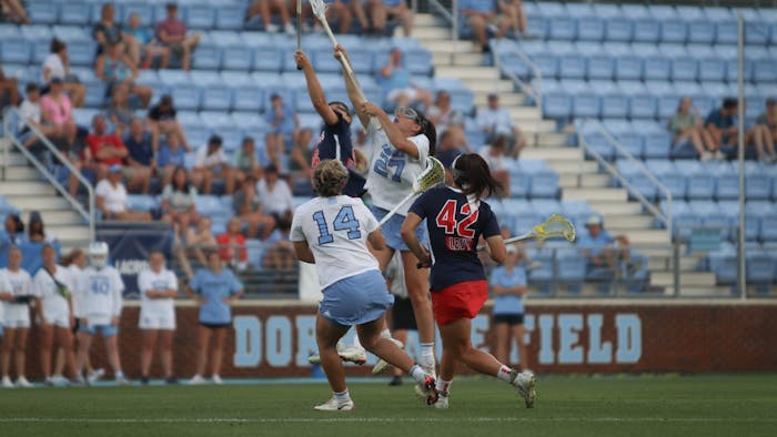 Junior midfielders Livi Lawton (14) and Olivia Dirks (27) run and jump for the ball during a faceoff in the NCAA quarterfinals. At halftime, UNC is losing 3-4 to Stony Brook.