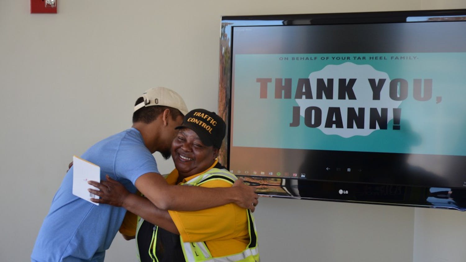 Crossing guard Joann Isom hugs UNC junior Carlos Salas after receiving money raised via GoFundMe for Isom to take a trip to visit her son. Salas set up the GoFundMe fundraiser after seeing Isom's story on the Humans of UNC Facebook page. 