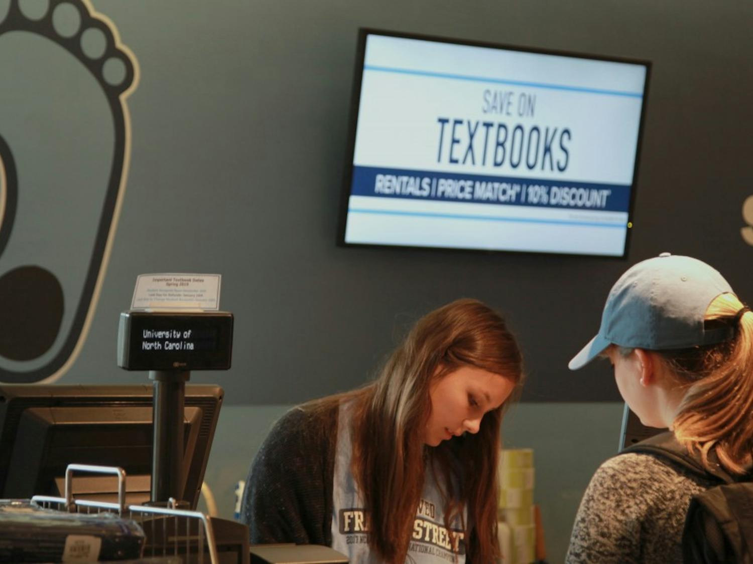 "Railey Pitts, a sophomore studying political science and business, helps another student with her textbooks on the lower level of UNC Student Stores. "