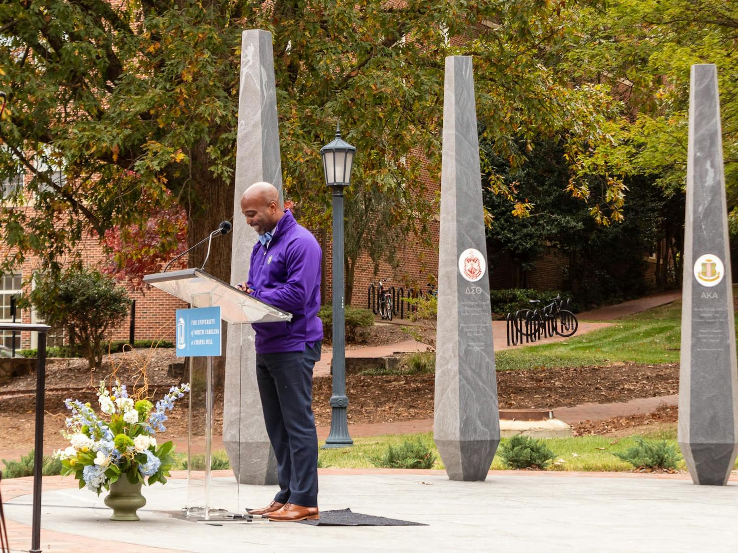 Zack Hawkins, the director of development for UNC Student Affairs, provides welcoming remarks to the dozens of people gathered in celebration of the opening of the NPHC Legacy Plaza on UNC's campus. The plaza represents the University's nine historically Black fraternities and sororities for their contributions to the campus community.