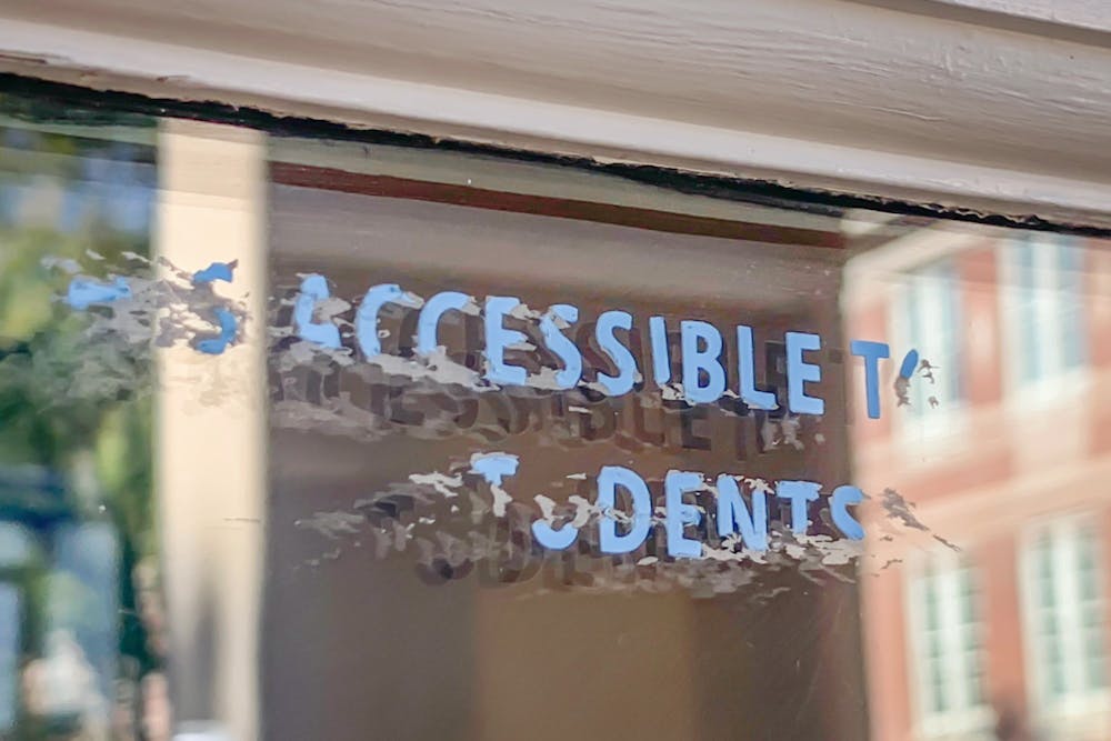 DTH Photo Illustration. A sticker on the front door of Carroll Hall once read "Is this accessible to all students?" but this message has been since scratched away.