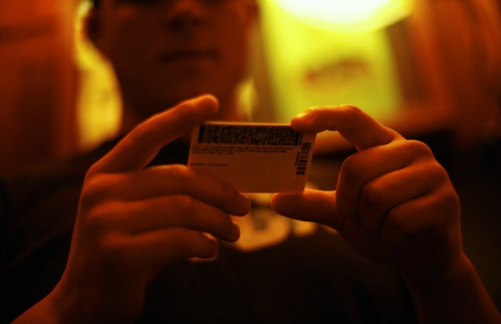 <p>Andrew Phillips, a senior EXSS major from Canton, Ohio, examines (my) ID at Goodfellows on Franklin St. The bar-back has worked at the bar for almost two years and says he can pretty quickly tell the difference between a real and a fake ID.&nbsp;</p>