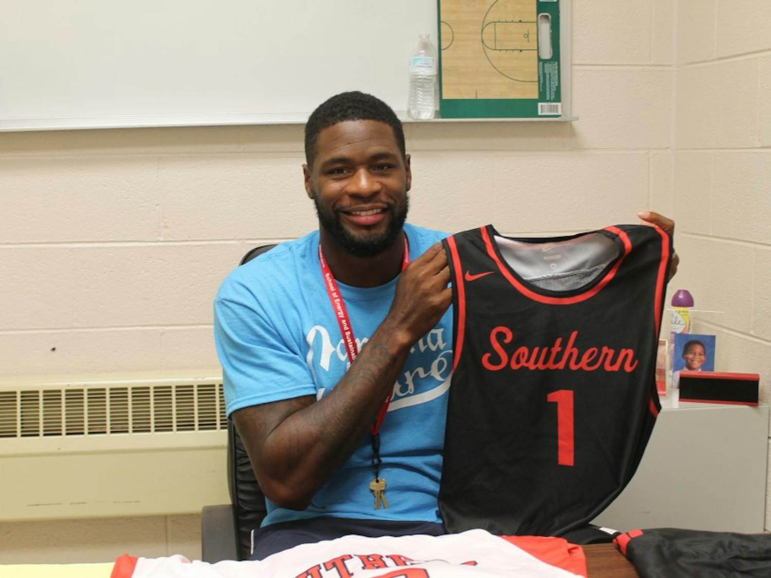 Southern Durham men's basketball head coach David Noel poses with a team jersey. Noel, who won a national championship with the UNC basketball team in 2005, returned to his former high school as a coach in late August.