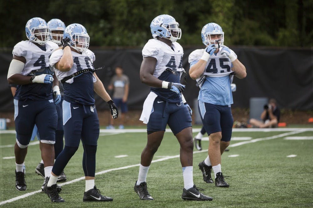 Tarheel Junior Gnonkonde, center, lines up to run through a play during practice on Tuesday, August 25, 2015.
