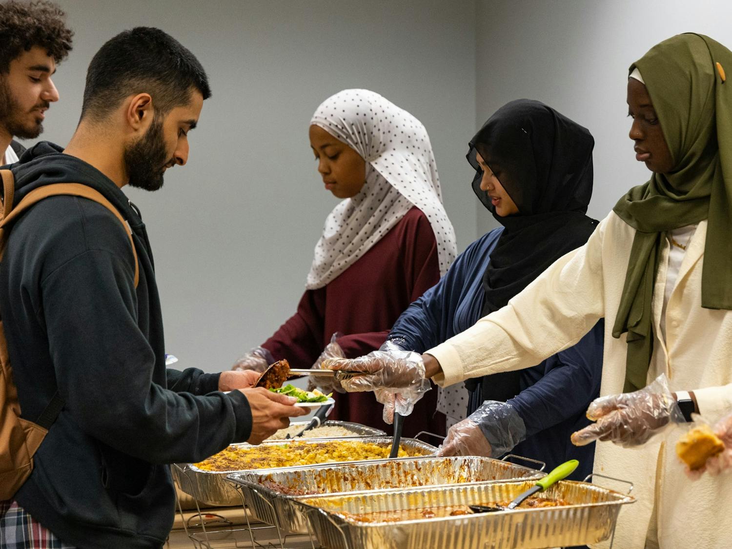 Sarah Jimenez, Miriam Matin and Ndumbeh Boye serve a variety of food, including macaroni and cheese and braised chicken, to students during Ramadan in Chapel Hill, N.C., on Monday, April 3, 2023. The UNC Muslim Student Association collaborated with Chef Jimenez to provide food for those breaking their fast after dusk.