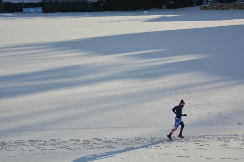 A runner circles the snow covered track on Fetzer Field.&nbsp;