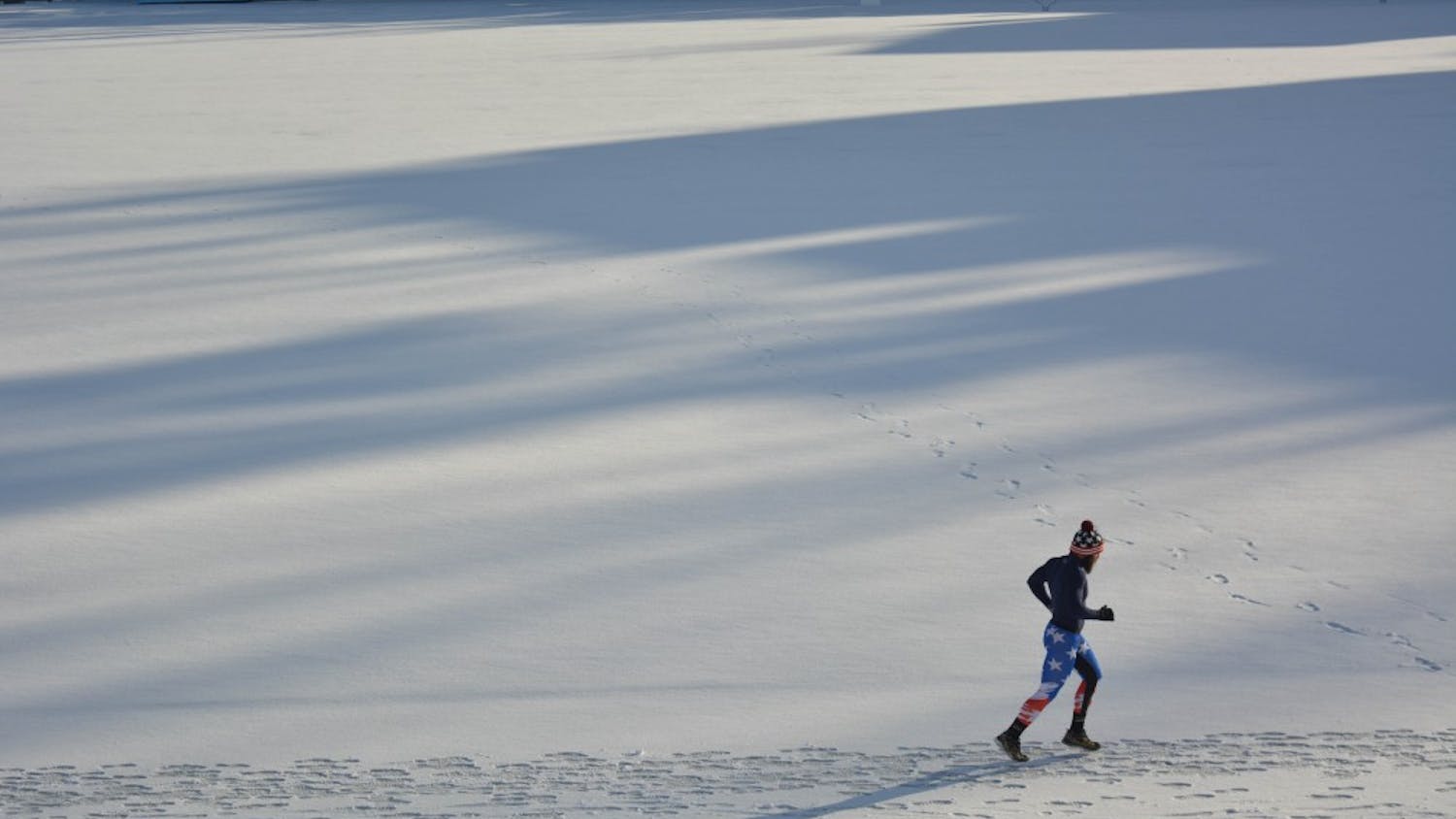 A runner circles the snow covered track on Fetzer Field.&nbsp;