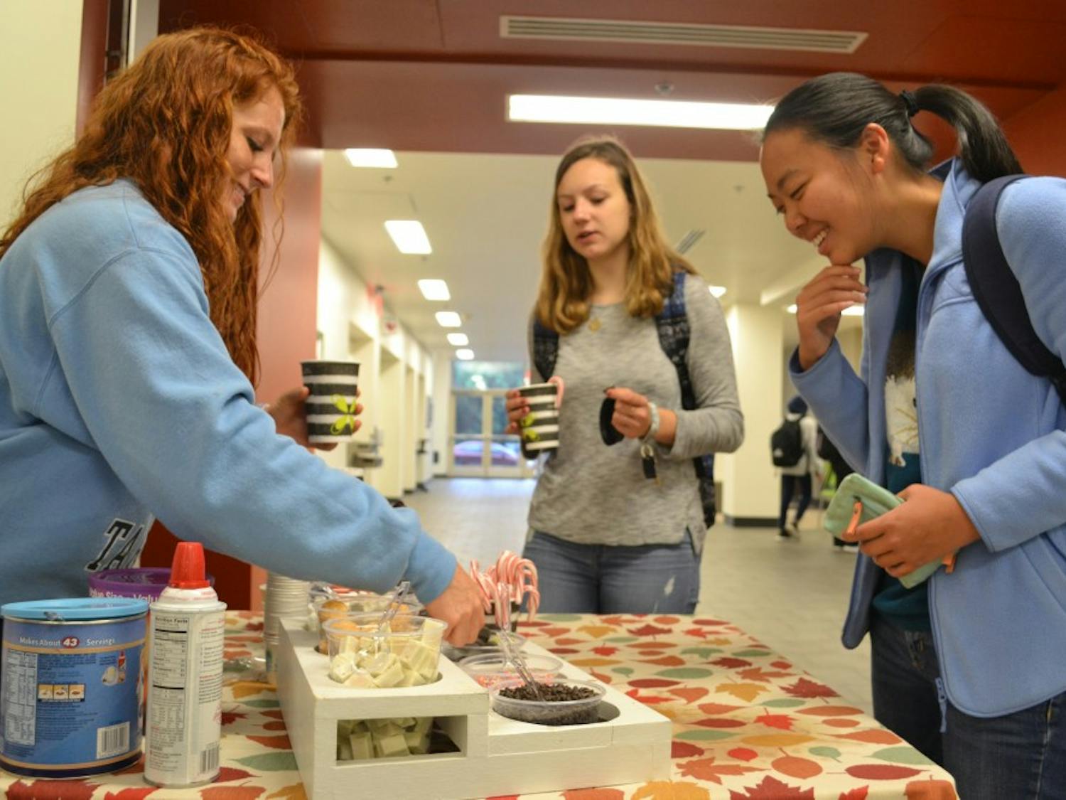 Maddy Munoz, a Loco Cocoa organizer, serves hot chocolate to UNC students Eileen Yang and Parker Novack at the Student Union on Tuesday morning.&nbsp;