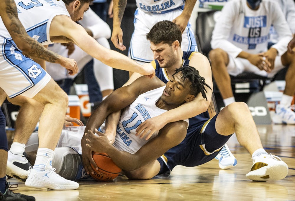 Carolina's Day'Ron Sharpe (11) battles Notre Dame's Matt Zona (25) for a loose ball on Wednesday, March 10, 2021 in Greensboro, N.C. Photo courtesy of Andrew Dye/Winston-Salem Journal