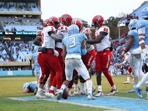 Linebacker Dominique Ross (3) plunges into a sea of NC State's offense to spark the post-game brawl on Saturday, Nov. 24, 2018 in Kenan Memorial Stadium.