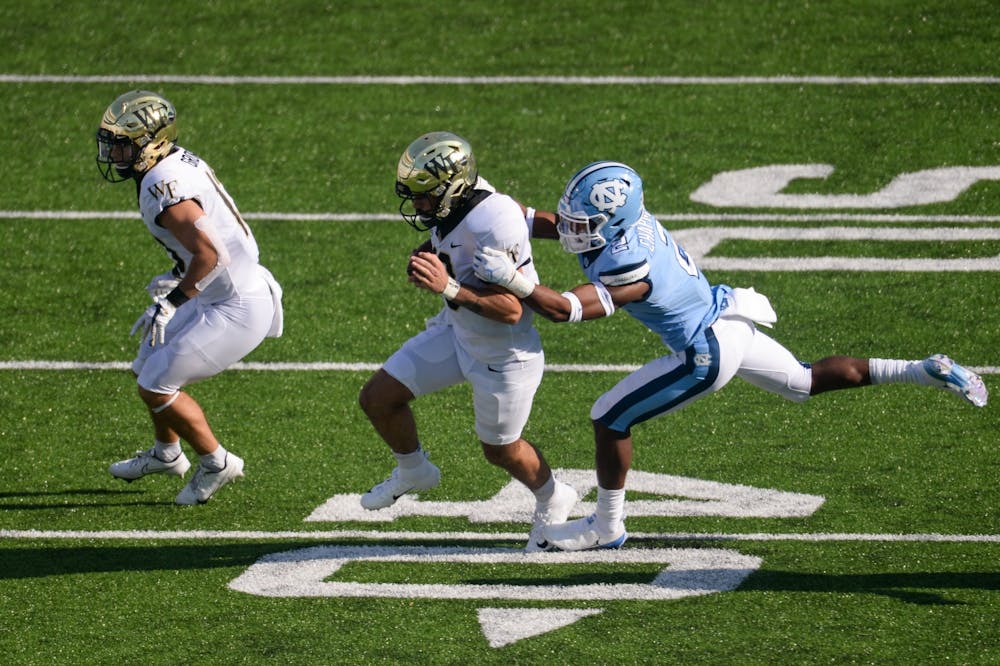 UNC' sophomore defensive back Don Chapman (2) grabs Wake Forest's redshirt sophomore quarterback Sam Hartman (10) during a game in Kenan Memorial Stadium on Saturday, Nov. 14, 2020. UNC beat Wake Forest 59-53.