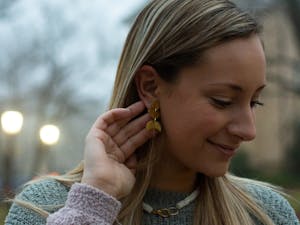 Anna Jordan, ‘22, the owner of AnnaBanana Jewelry, shows off a pair of earrings from her newest collection on February 15, 2021 at McCorkle Place. Jordan used to make faux leather pieces, she said, but now the business focuses on clay and resin jewelry.