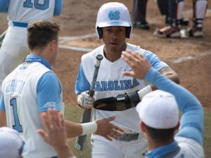 Sophomore outfielder Justice Thompson (20) gets high fives from teammates after stealing home against University of Virginia on Saturday, Feb. 27, 2021. The Tar Heels beat the Cavaliers 2-1.