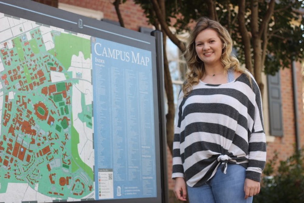 Kamryn Sain, a legacy student, smiles by a UNC campus map on Wednesday, Feb. 13, 2019. Both of Sain's parents attended UNC.